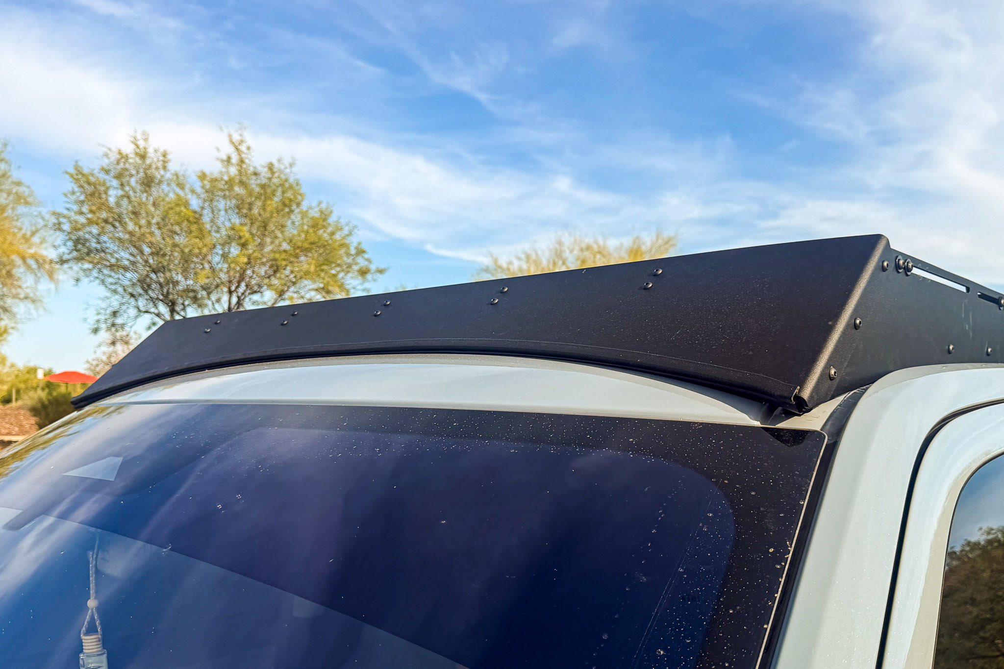 overland-expedition-suv-camping-gear-setup.jpg Close-up detail of the aerodynamic wind fairing mounted on the front of an aluminum overlanding roof rack on a Ford Expedition